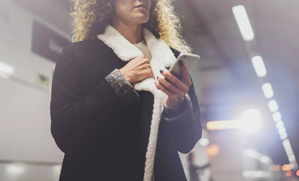 Mujer viajera enviando mensajes de texto a un teléfono inteligente mientras espera con una maleta en un aeropuerto o una estación de tren —  Fotos de Stock