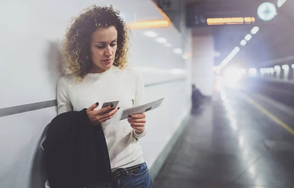 Mujer viajera enviando mensajes de texto a un teléfono inteligente mientras espera con una maleta en un aeropuerto o una estación de tren —  Fotos de Stock
