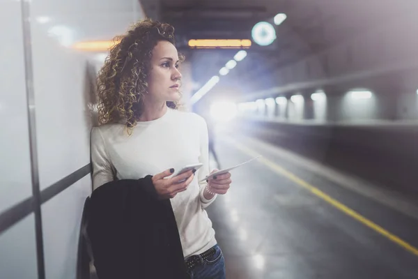 Mooie vrouw op pendelen doorgang met behulp van smartphone terwijl je in de treinstation. Aantrekkelijk meisje gelukkig met mobiele telefoon app voor gesprek in vakantiereizen. — Stockfoto