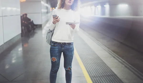 Mujer viajera enviando mensajes de texto a un teléfono inteligente mientras espera con una maleta en un aeropuerto o una estación de tren — Foto de Stock