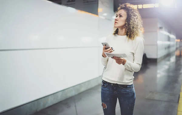 Aantrekkelijke vrouw op doorgang met behulp van de smartphone tijdens het wandelen met handbagage rugzak in treinstation of airpot gonna boardinggate. Geniet van de spoorweg vervoer concept. — Stockfoto