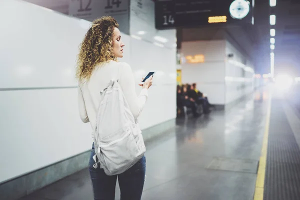 Piękna dziewczyna na szczęśliwy, za pomocą aplikacji telefon komórkowy dla konwersacji w wakacyjnych podróży. Atrakcyjna kobieta na platformie tranzytu przy użyciu smartfona podczas oczekiwania na pociąg kolei na stacji. — Zdjęcie stockowe