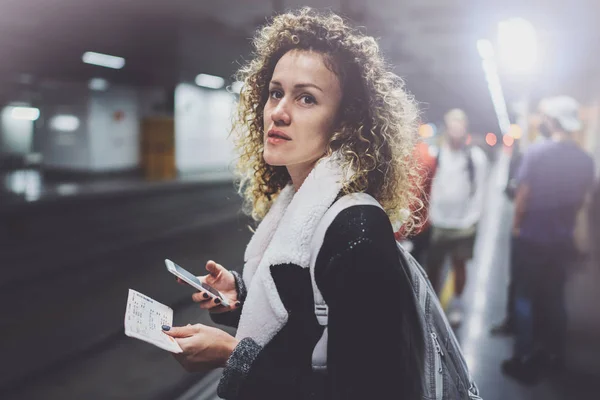 Aantrekkelijke vrouw met rugzak op doorreis platform met behulp van smartphone voor foto van treinticket maken tijdens het wachten rail trein op metrostation. — Stockfoto