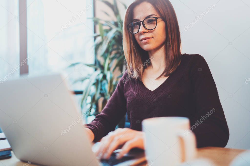 Young entrepreneur girl using mobile laptop for looking a new business solution during work process at night office.Blurred background.
