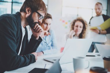 Sakallı işadamı güneşli toplantı odasında muhabbet iş ekibi ile. Horizontal.Blurred arka plan.