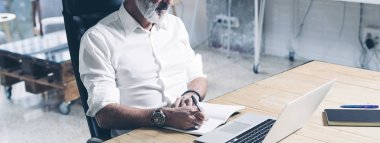 Modern coworking ofiste tahta masada çalışırken mobil dizüstü bilgisayar kullanan çekici ve confidental yetişkin iş adamı. Geniş.
