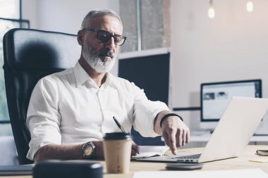 Modern coworking ofiste çalışan dalgın iş adamı. Çağdaş mobil dizüstü kullanan kendine güvenen adam.