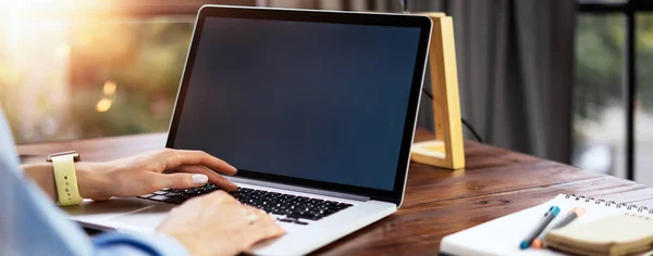 Εικόνα mockup μιας γυναίκας που χρησιμοποιεί laptop με λευκή οθόνη σε ξύλινη — Φωτογραφία Αρχείου