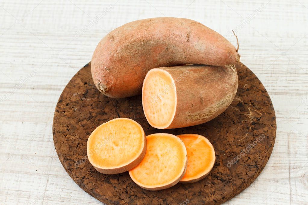 Raw sweet potatoes on wooden background