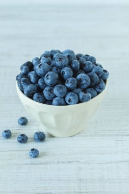 Ahşap masa üzerinde beyaz bir kase içinde yaban mersini