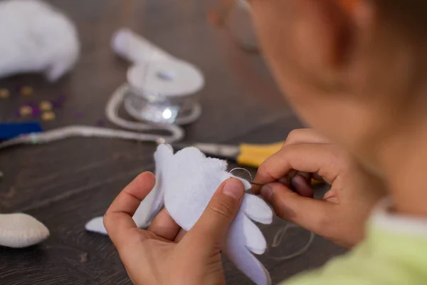 Hands of little girl making a rag doll — Stock Photo, Image