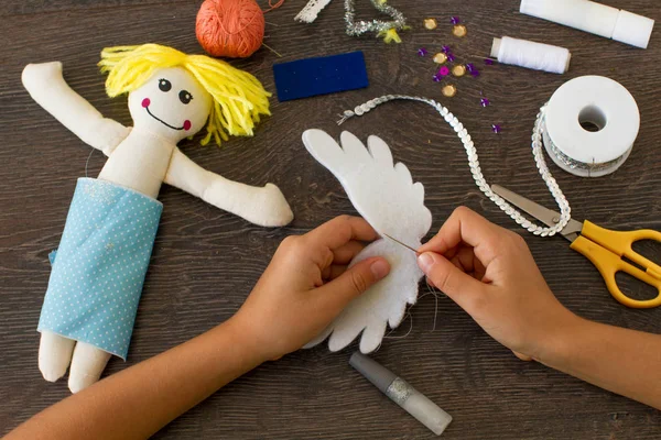 Руки маленькой девочки делают тряпичную куклу — стоковое фото