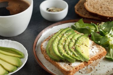 Koyu siyah ekmek ekmek taze doğranmış avokado, krem peynir ve tohum, yukarıda yapılan üzerinde avokado sandviç