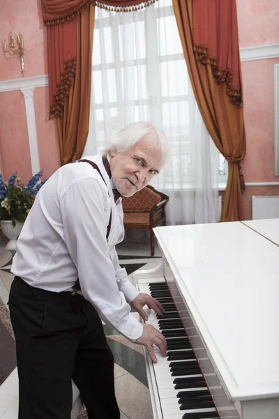 Зрілий музикант грає на білому піаніно — стокове фото