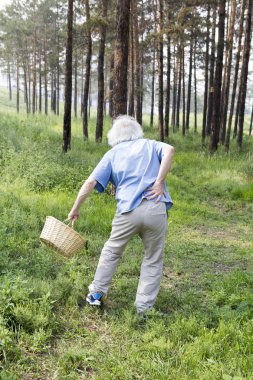 Yaşlı bir adam sırt ağrısı ile yürüyüşte