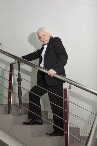 A man in a tuxedo on a metal ladder — Stock Photo, Image