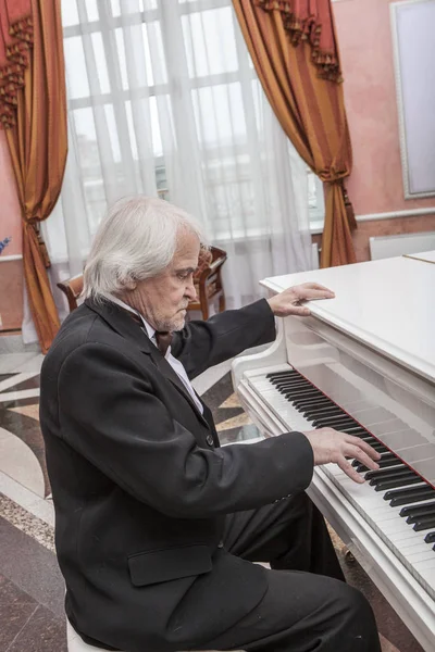 Mature musician playing a white piano — Stock Photo, Image