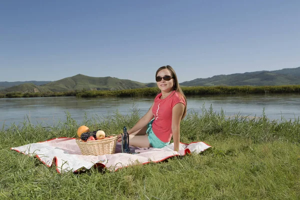 Jovem mulher descansando no banco de um lago é — Fotografia de Stock