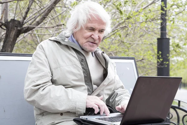 Homem sênior usando computador portátil ao ar livre — Fotografia de Stock