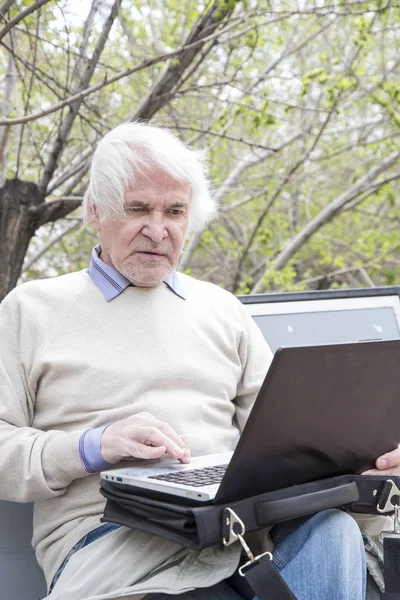Homem sênior usando computador portátil ao ar livre — Fotografia de Stock