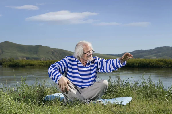 老人坐在河岸上 — 图库照片