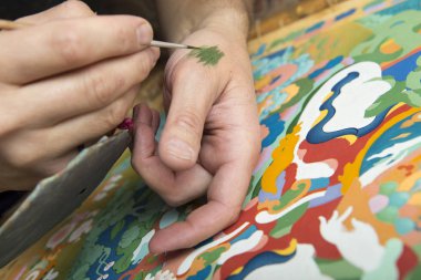 Sanatçı bir Budist kutsal kişilerin resmi boyar