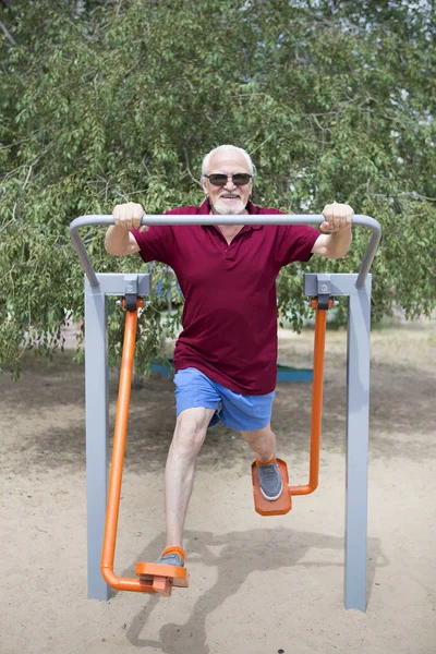 Hombre mayor entrena en equipos deportivos al aire libre —  Fotos de Stock