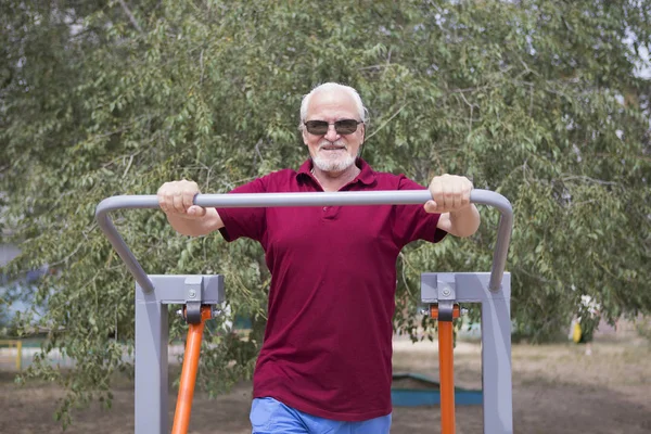 Hombre mayor entrena en equipos deportivos al aire libre —  Fotos de Stock