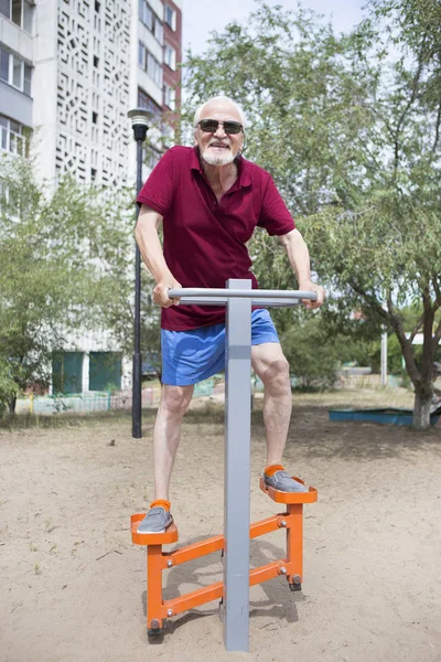 Senior man trains on sporting equipment on open air