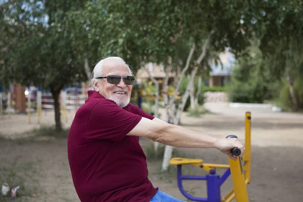 Senior trainiert an Sportgeräten unter freiem Himmel — Stockfoto