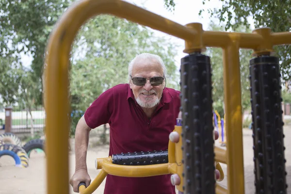 Senior man tåg på sportutrustning på open air — Stockfoto