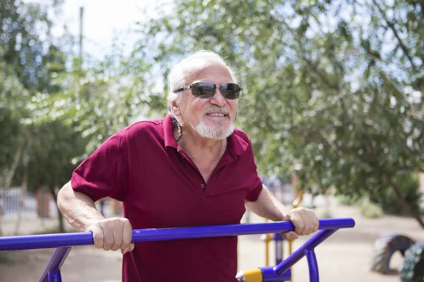 Senior man trains on sporting equipment on open air