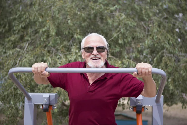 Starszy człowiek pociągi na sportowy sprzęt na świeżym powietrzu — Zdjęcie stockowe