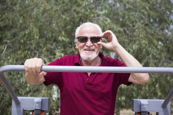 Старший чоловік тренує спортивне обладнання на відкритому повітрі — стокове фото