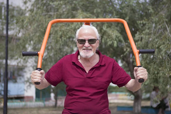 Starszy człowiek pociągi na sportowy sprzęt na świeżym powietrzu — Zdjęcie stockowe