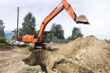 Ekskavatör bir hendek kazıyor. İnşaatta çalışıyorum. Siperler iletişim bina inşaat altında döşeme için.