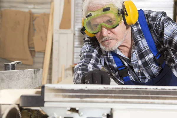 Worker using saw machine to make furniture at carpenters workshop. Handmade business at small furniture factory.