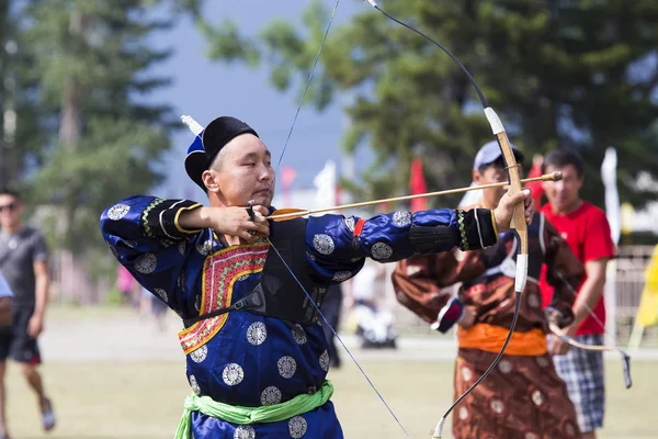 Competitions in shooting from a sports bow in Siberia. Mongolian competitions in archery. The sportsman is dressed in a traditional Buryat-Mongolian suit, shooting with his arrows during a national holiday.