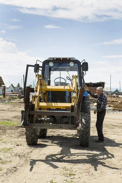 The driver of the tractor-loader prepares the unit for work.