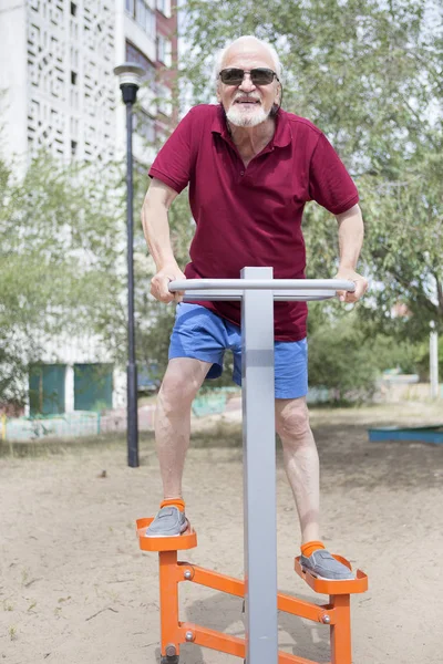Senior man trains on sporting equipment on open air
