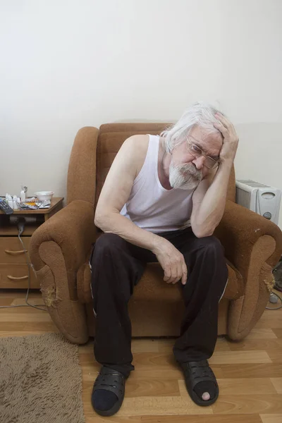 Old sick lonely man in the armchair at home