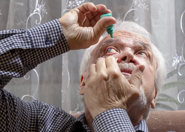 Elderly man buries medicine in his eyes — Stock Photo, Image
