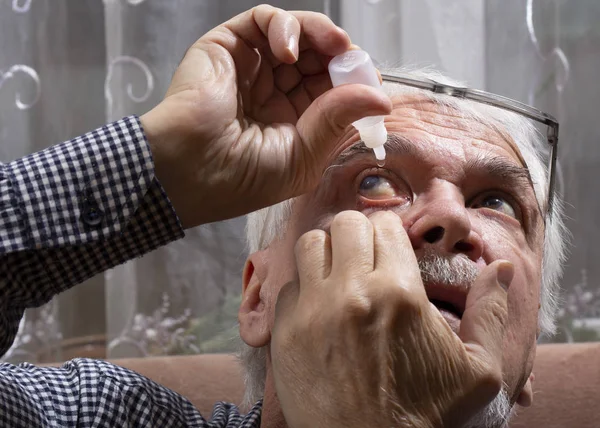 Пожилой человек закапывает лекарство в глаза — стоковое фото