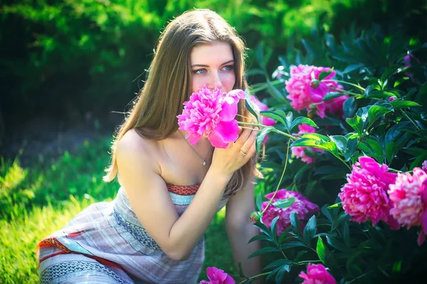 Een aantrekkelijke jonge vrouw zit en geniet van de geur van bloemen — Stockfoto