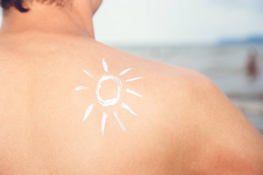 Güneş deniz arka plan üzerinde güneş koruyucu losyon adamla