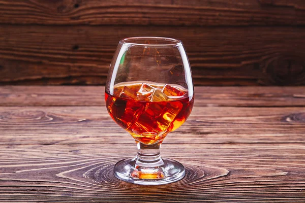 Whisky coñac con cubitos de hielo en un vaso sobre un fondo de madera —  Fotos de Stock