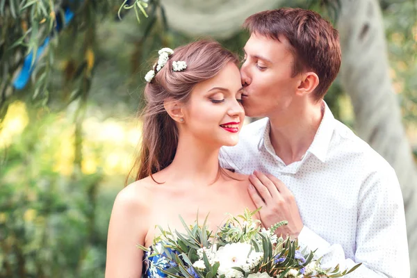 Glückliche junge Brautpaar Mann hält Hand und küsst seine Frau — Stockfoto