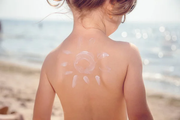 Loción niña con protector solar con sol sobre el fondo del mar — Foto de Stock