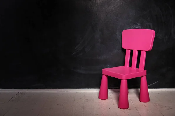 Rosafarbener Stuhl auf dunklem Hintergrund auf dem Holzboden — Stockfoto