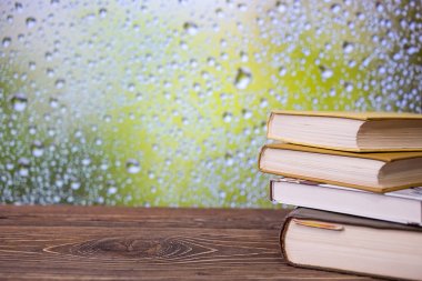 Yağmurlu bir gün pencere arka plan üzerinde bir retro ahşap masa kitap